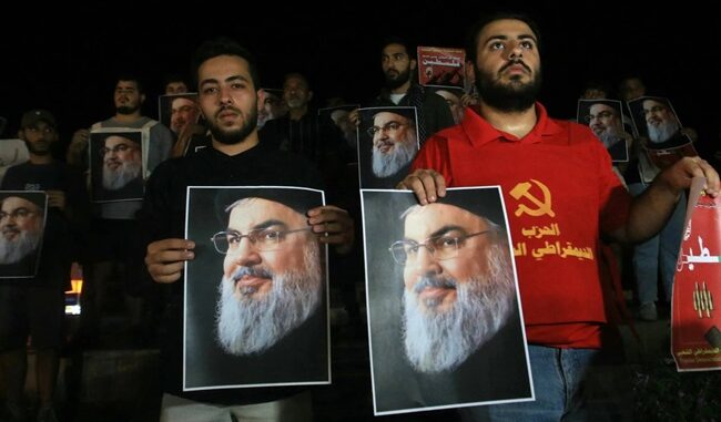 Des manifestants tenant des photos de Hassan Nasrallah, lors d'une veillée de protestation dans le sud du Liban, le 28 septembre 2024